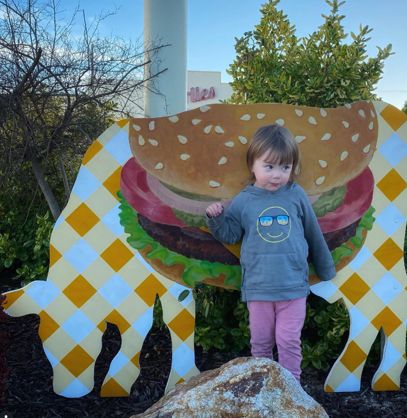 Child standing in front of Charlies burger sign